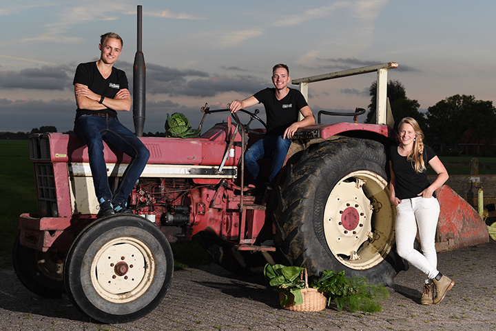 Farmers who are part of the cooperative de Streekboer standing in front of a red tractor.