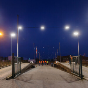 DUAL Ports decarbonises small to medium sized ports: Intelligent LED lighting in the Port of Emden Strong lighting in harbour area at night, with people in safety vests.