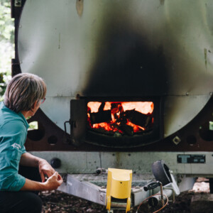 CANAPE uses this charcoal burner to turn waste wood from conservation management into biochar - sustainable, high quality charcoal. Conservation waste wood is often burned in open fires as it has no commercial value. Conservationist watching as a charcoal burner turns waste wood is turned into biochar in the charcoal burner.