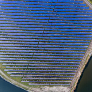 In DUAL Ports, the Danish port of Hvide Sande and Hvide Sande District Heating are working together to create a system of sustainable energy. A “Power to X” system that accelerates the green transition and produces green energy for citizens and businesses. Aerial view of a land area filled with blue solar panels.