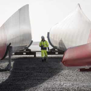 Inn2POWER: Based on 2018 figures, the offshore wind industry and its supply chains account for 200,000 jobs in the North Sea Region alone. However, the demand for qualified personnel in the offshore wind industry remains high. This photo symbolises the importance of trained staff in an expanding industry. In addition to engineering and technology skills, management capacity needs to increase as well. Therefore, Inn2POWER developed the first MBA programme specifically for the offshore wind industry. A worker walking in between wind turbine blades stored on the ground.