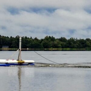 Predicting climate impacts: TOPSOIL uses an innovative floating device for 3D-mapping of structures 3070 m below the bottom of the lake. Photo: Aarhus University. A lake with people in a boat, towing a technical device that maps the underground structures below the lake.