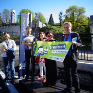 SHARE-North: Celebration of the opening of the first mobil.punkt (shared mobility hub) in Bergen, Norway. A group of people holding a banner promoting shared mobility.