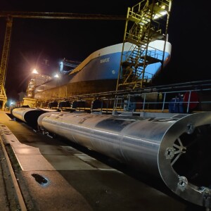 WASP: Here you can see that the ship of one of the project beneficiaries is moored and the Wind Assisted Ship Propulsion technology, the VentiFoil, is on the quay at the shipyard. The green product is ready to be installed on the vessel. Large cylinders for wind-assisted shipping lying on the quay next to the vessel they will be fitted on.