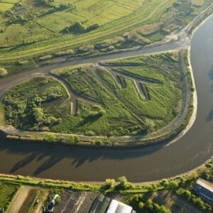 IMMERSE: Implementation site in the Scheldt estuary at
Wijmeers, Wichelen (Flanders) of IMMERSE
partner Flemish Waterways plc. A side channel
was created to widen an upstream part of the
river which can reduce the incoming tidal wave
energy by spreading it over a larger cross-section
with a higher resistance. Photo: Yves Adams Aerial photo of estuary with a brownish river and green landscape