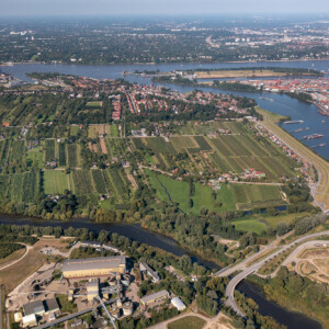 IMMERSE: The extent of the estuary flood space can help to
mitigate estuarine pressures at the Elbe (e.g. by
reconnecting cut-off anabranches like Alte
Süderelbe). We explore solutions involving
stakeholders for the challenge of sustainably
and cost-effectively secure navigation while
improving the functions of the estuarine system. Photo: BAW Aerial photo of a green landscape with a river and estuary.