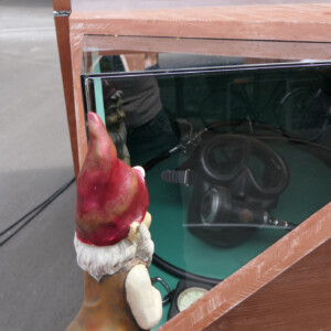 North Sea Wrecks: concept for children: Gulliver, the garden gnome, tells children the story of the North Sea Wrecks project (NSW). Here he explores the NSW exhibition. Photo: Cornelia Riml Garden gnome peers into a wooden box containing diving gear from the past.