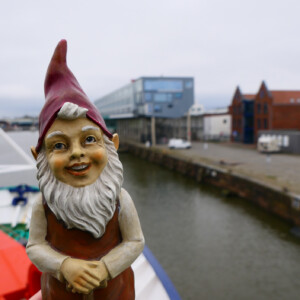 North Sea Wrecks: Communication concept for children: Gulliver, the garden gnome, tells children the story of the North Sea Wrecks project (NSW). He was part of the European research cruise team and was on board of the research vessel HEINCKE. Garden gnome in front of harbour.
