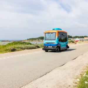 PAV: Achieving sustainable travel across Europe with self-driving vehicles. A small autonomous bus in blue and orange colours