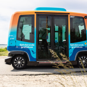 PAV: PAV: Stimulating the uptake of shared autonomous vehicles with sustainable mobility solutions. A blue and orange autonomous bus on the road